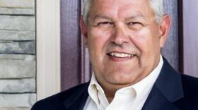 a headshot of a man in a suit who is smiling