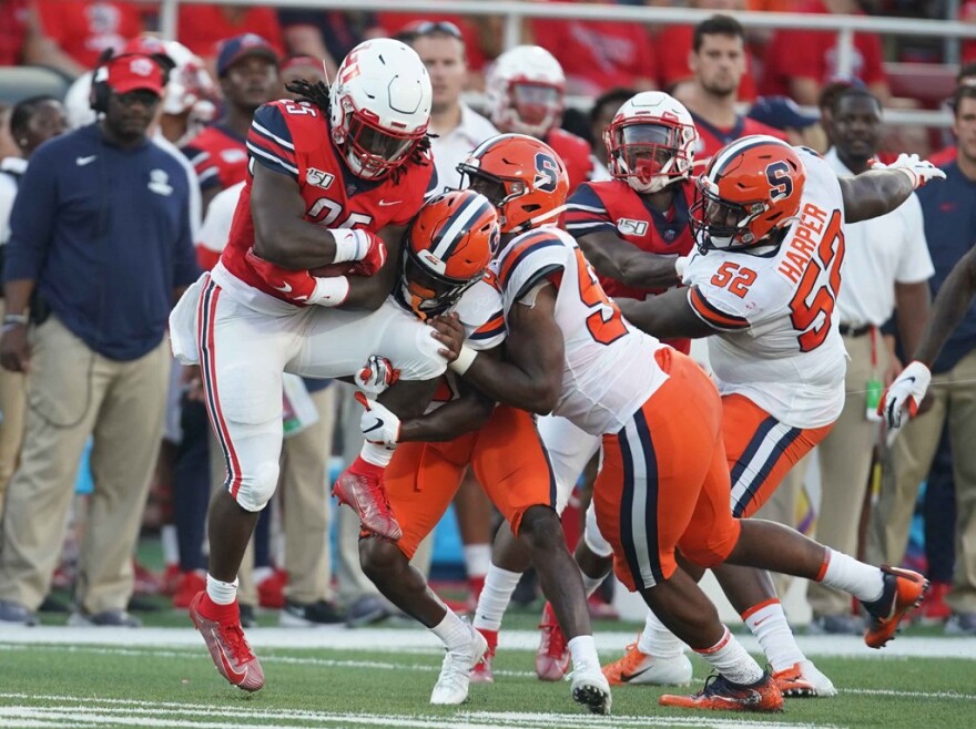 LU running back Peytton Pickett (red) is swallowed up by a pair of SU tacklers (white) last season.