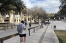 A student in a ball cap and backpack walks down a ramp towards the sombrilla on the main campus of UT San Antonio in March 2026.