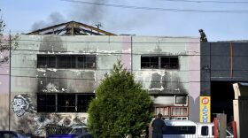 A firefighter walks on the roof of a smoldering building after a fire tore through a warehouse party early Saturday, Dec. 3, 2016 in Oakland. (Josh Edelson/AP)