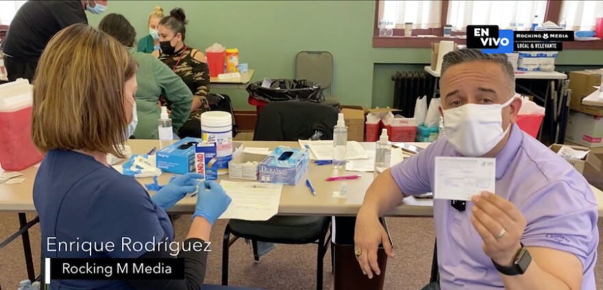 A screenshot of Enrique Rodriguez Franz holding up a card confirming his COVID-19 vaccination.
