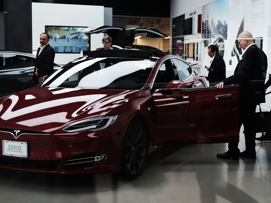 People look at cars at a Tesla showroom in New York City. Tesla CEO Elon Musk, reportedly under scrutiny by federal regulators for earlier statements, says Saudi Arabia's sovereign wealth fund is looking to diversify away from oil with a bigger investment in the electric car company.