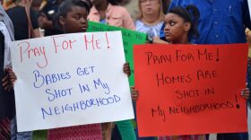 Twins Jada and Jaelyn Weems spend their birthday holding signs during the vigil. They live close to Ocala Place Apartments, where some of the shootings have occurred.