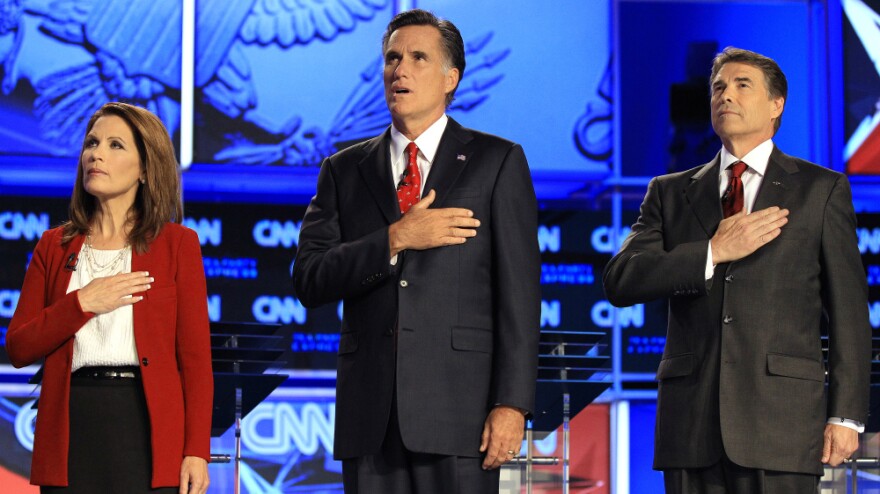 Republican presidential candidates (from left) Rep. Michele Bachmann, former Massachusetts Gov. Mitt Romney and Texas Gov. Rick Perry cover their hearts during the playing of the national anthem before a Republican presidential debate on Sept. 12.