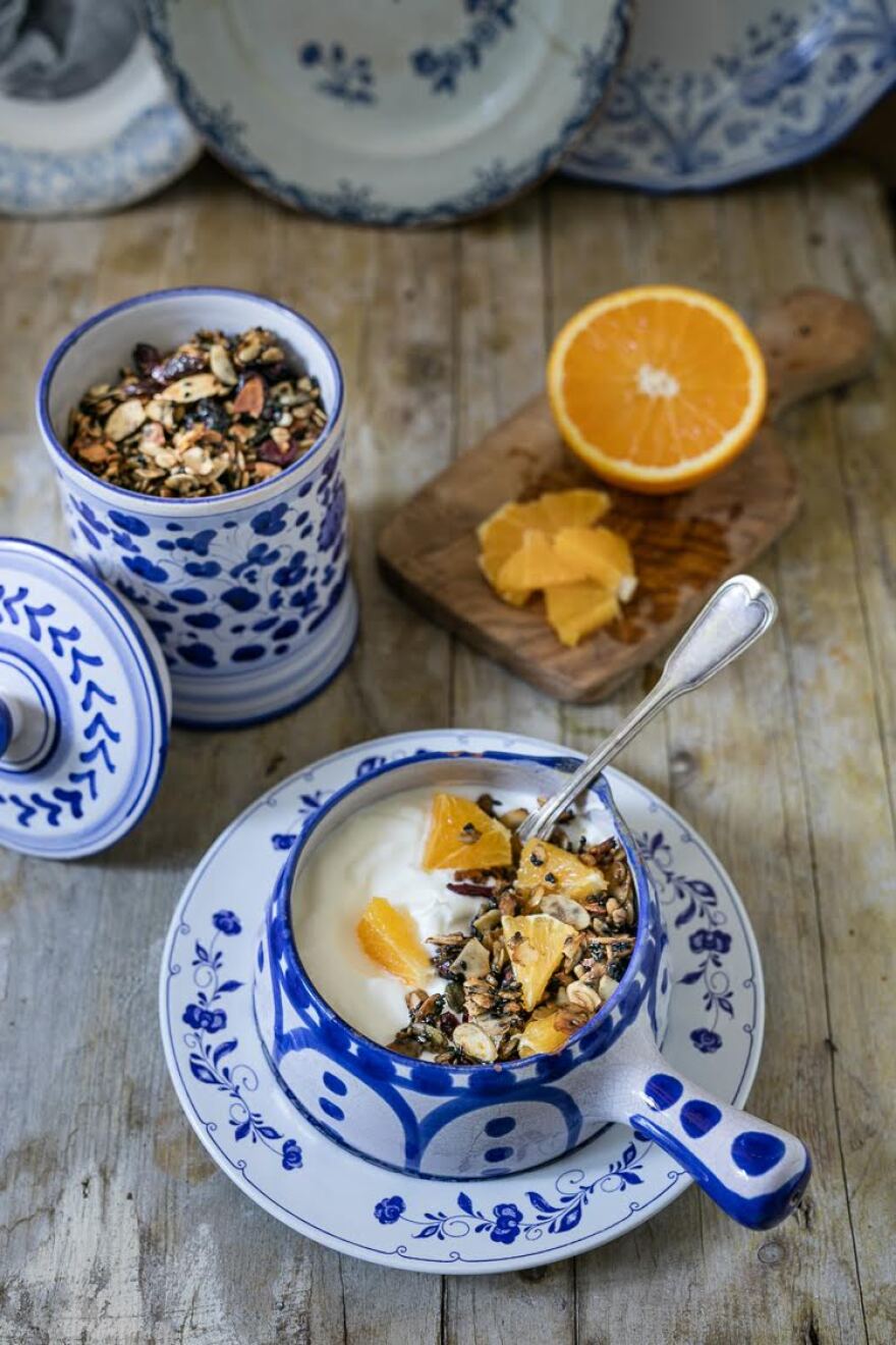 Two bowls of granola and an orange on a table