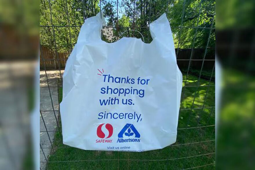 A plastic bag hanging from a fence. The bag reads: "Thanks for shopping with us" and includes two corporate logos.