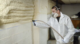 A Weatherization Tech sprays a two-part spray foam on the basement walls and box sill at a home in Yarmouth, Maine.