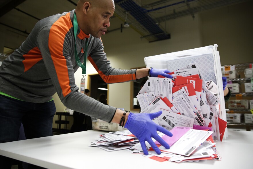 An election worker in Renton, Wash., begins processing mail-in ballots during that state's presidential primary in March. Varying state-by-state requirements around signatures and other rules have become the focus of legal fights as absentee voting expands due to the pandemic.