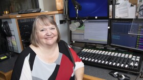 Host Danna O'Connor in the KUNR studio. She is holding a pair of headphones and looking toward the camera while smiling.