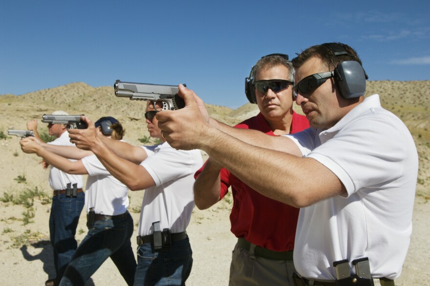 Instructor assisting officers with hand guns at firing range during weapons training.