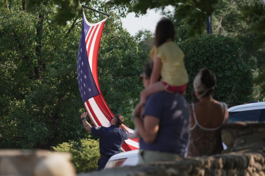 A flag hangs in front of a large crowd of people.