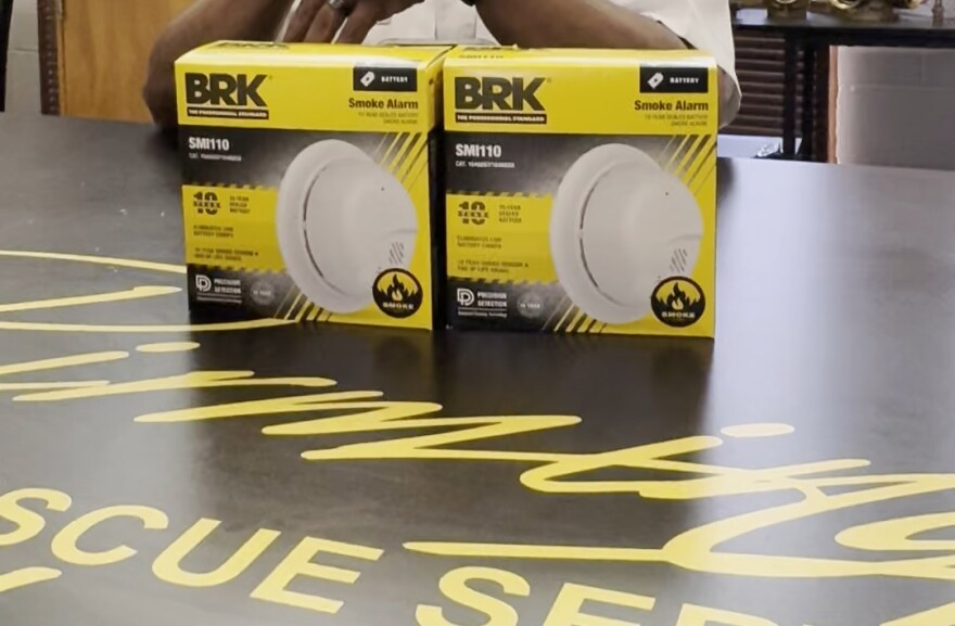 Two smoke-detector boxes are displayed on a table. A picture of a circular, white smoke alarm is printed on the boxes, which have a yellow and black color scheme and BRK branding.