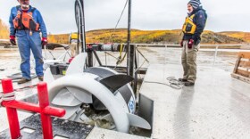 ACEP research engineer Jack Schmid, left, and research professional Paul Duvoy help position the Oceana river turbine suspended from a barge during testing in the Tanana River near Nenana conducted in 2016 by ACEP’s Hydrokinetic Energy Research Center.