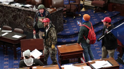 Larry Rendall Brock Jr., an Air Force veteran, is seen inside the Senate Chamber wearing a military-style helmet and tactical vest during the rioting at the U.S. Capitol. Federal prosecutors have alleged that before the attack, Brock posted on Facebook about an impending "Second Civil War."