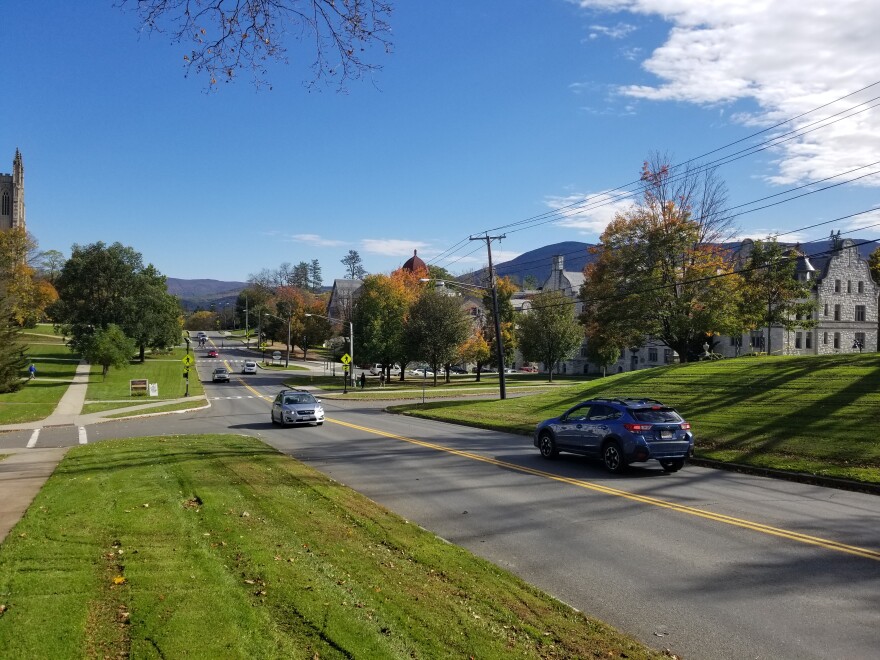 Cars drive on a road in a small New England town.