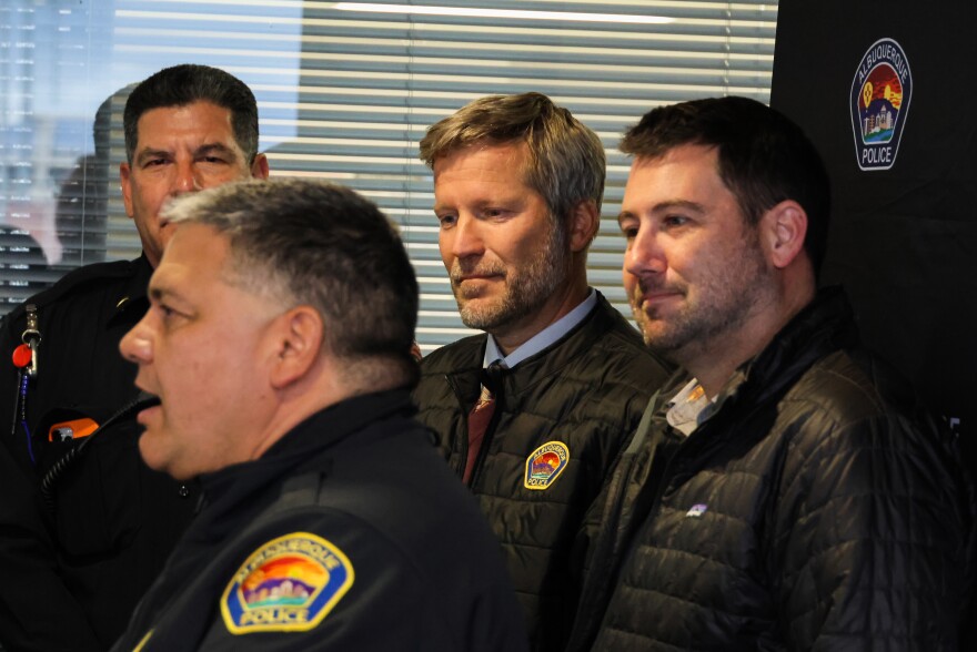 Albuquerque Mayor Tim Keller (right) and City Council President Pat David (left) listen as Police Chief Harold Medina addresses the media