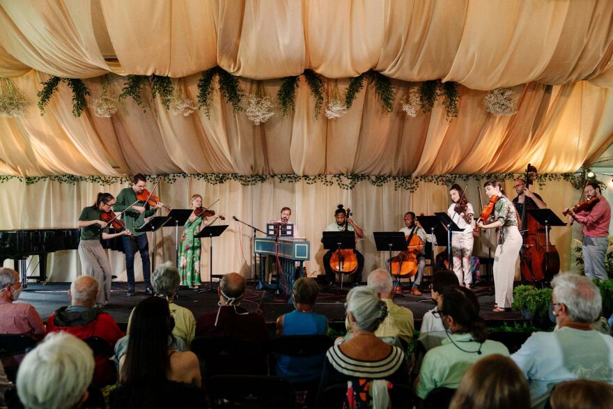 Palaver Strings performing on an outdoor stage in summer.