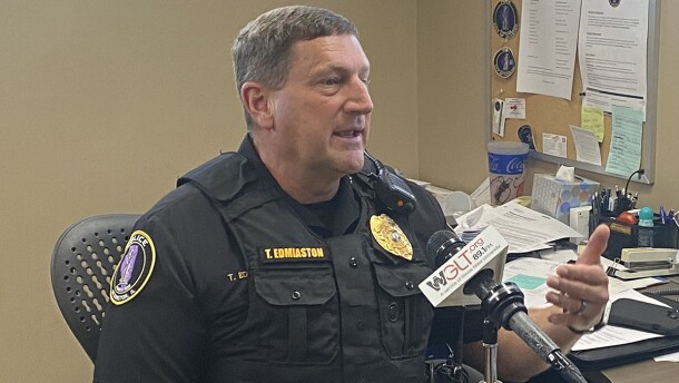 Police officer sits at his desk speaking into a microphone