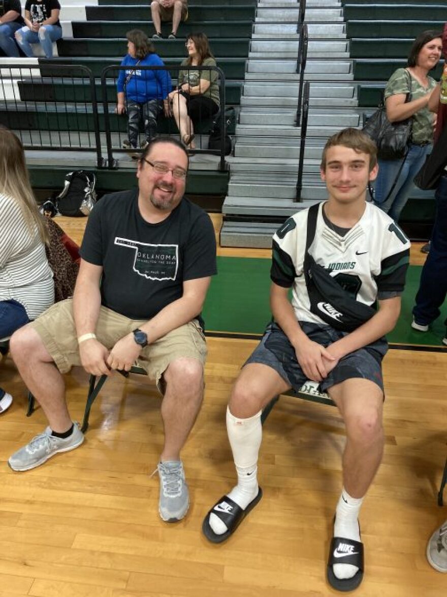 John Reininger, with his son Ryjan Reininger sit together before the start of a ceremony to reveal Oklahoma School for the Deaf’s new Bison logo.