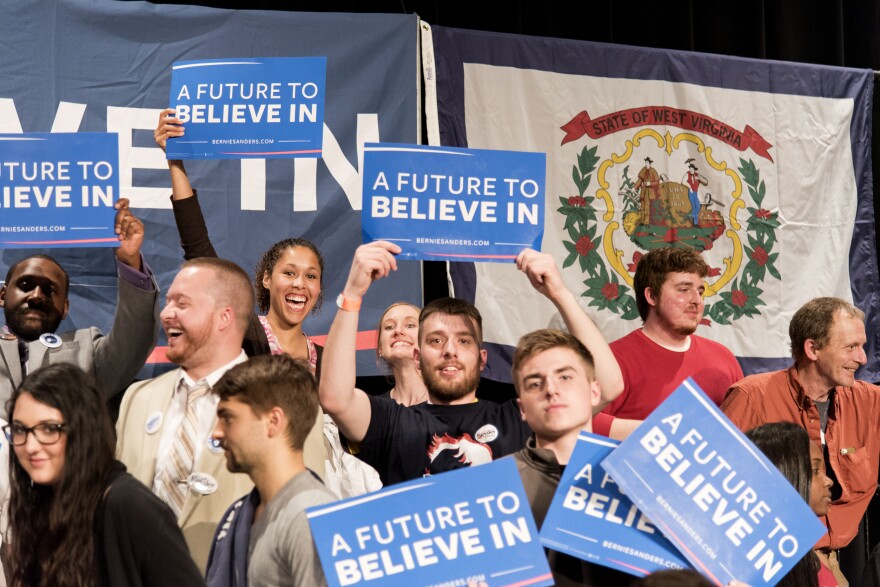 Megan Collins (top row, holding highest sign) stands behind Bernie Sanders' podium Thursday, May 5, at the Morgantown Event Center.