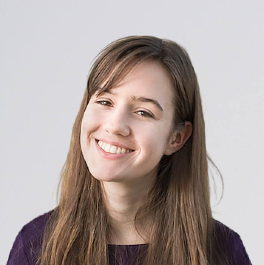 A smiling young woman has long brown hair.