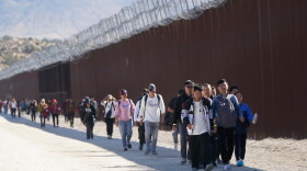  A group of people walk along the wall after crossing the border with Mexico in 2023