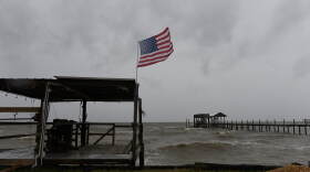 Una bandera estadounidense ondea al viento provocado por los efectos del huracán Isaías en una playa vacía, el 9 de octubre de 2026, en Mon Louis Island, Alabama. (AP Foto/Octavio Jones)