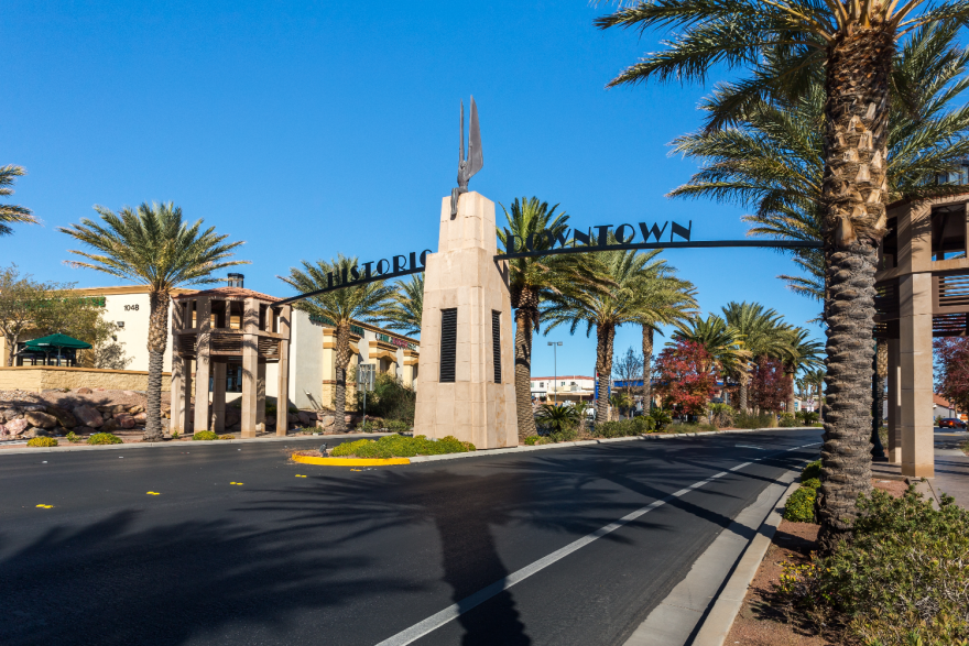 Street-side view of a gateway arch entry that says "historic downtown" with a statue of a person with wings in the center.