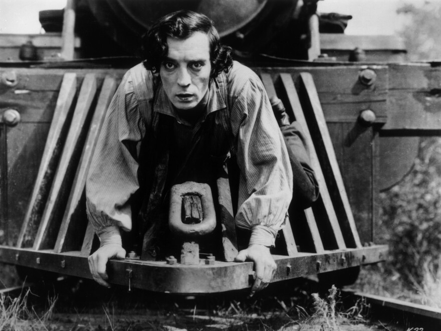 American actor Buster Keaton clinging to the front of a train in a still from the 1926 film, 'The General.'