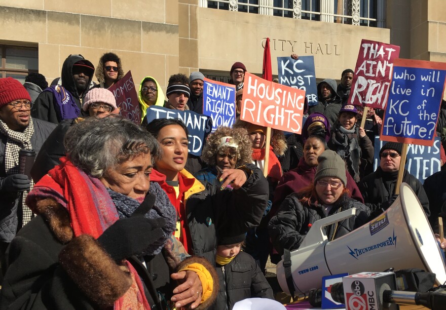 Dozens of protestors bundled against the cold, some holding signs, at a tenants rights protest in front of a city hall building.