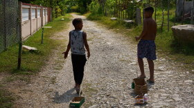 Children drag toys made from cardboard boxes as they walk in Minas, in Cuba's Havana province, Monday, Aug. 31, 2026.