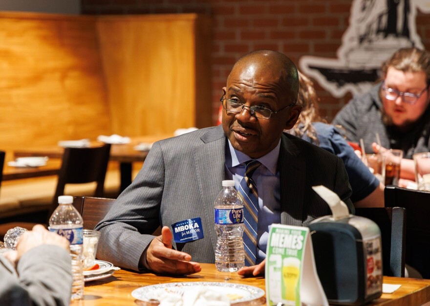 Mboka Mwilambwe seated at a restaurant table talking with someone