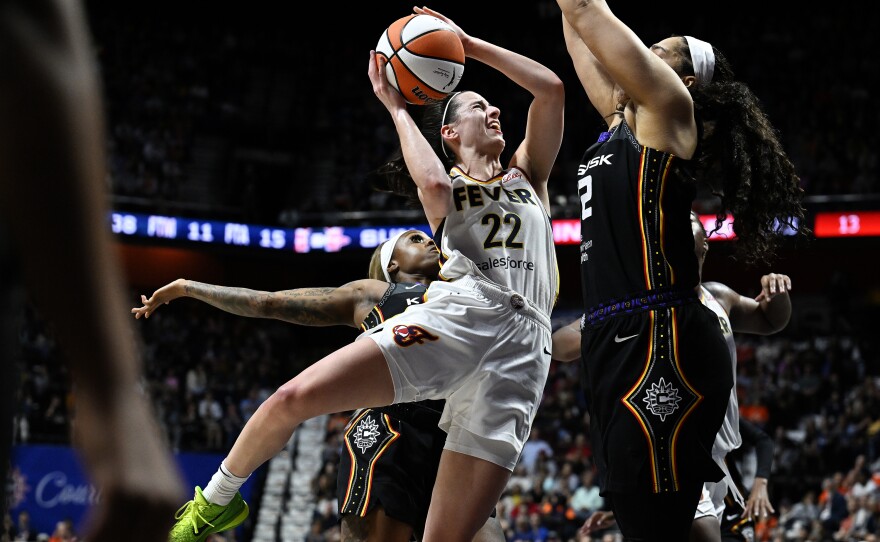 Indiana Fever guard Caitlin Clark (22) is fouled from behind by Connecticut Sun guard Tiffany Mitchell (3) as she drives against forward Brionna Jones (42) during the fourth quarter of a WNBA basketball game, Tuesday, May 14, 2024, in Uncasville, Conn. 