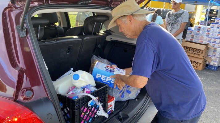 Volunteers load food in the backs of vehicles at a food distribution event at Wings of Faith Fellowship Church near Ocala.