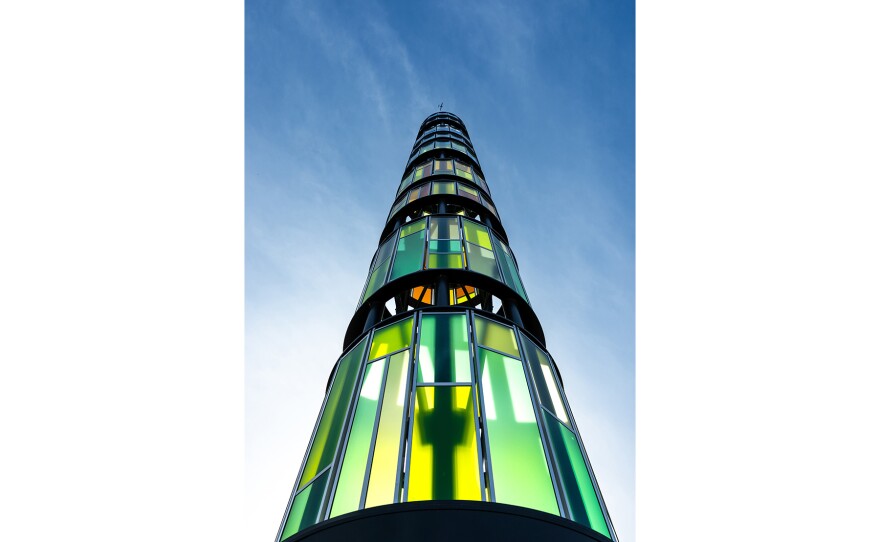 A tower constructed of green glass against a blue sky
