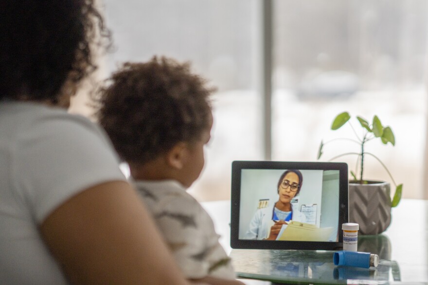 Mother on a remote medical call with a doctor about her sick child (via iStock)