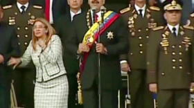 Venezuelan President Nicolas Maduro (center) watches drones explode overhead last Saturday in Caracas along with his wife Cilia Flores (left) and military guards.