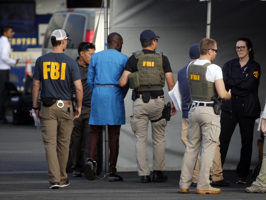 Federal agents hold a detainee (second from left) at a downtown Los Angeles parking lot after predawn raids in the L.A. area on Thursday.