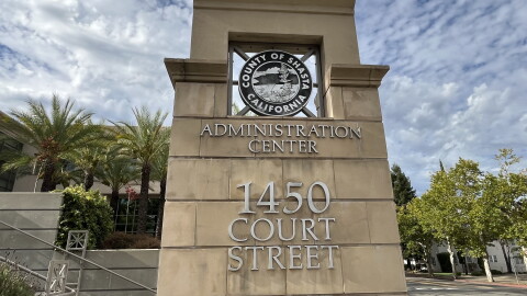 A large stone marker outside reads 'administration center' with the address. Behind are palm trees and blue sky. 