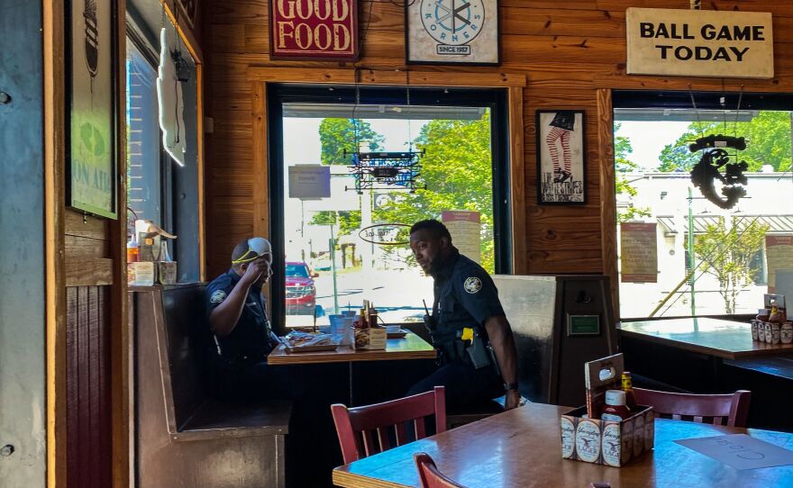 Two police officers get something to eat at Moe's Original BBQ restaurant in late April in Atlanta afte limited dine-in service was allowed under loosened state coronavirus restrictions.