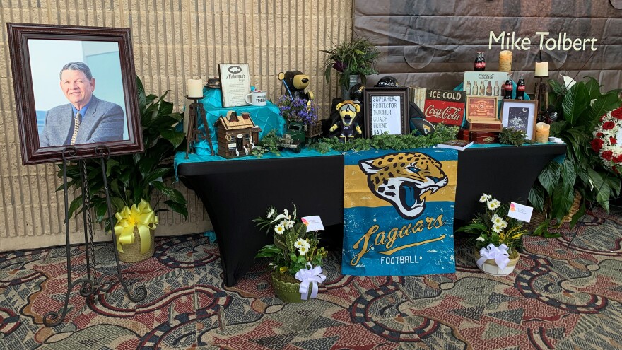 A table with Jacksonville Jaguars memorabilia, and a picture of Godbold in the convention center lobby.