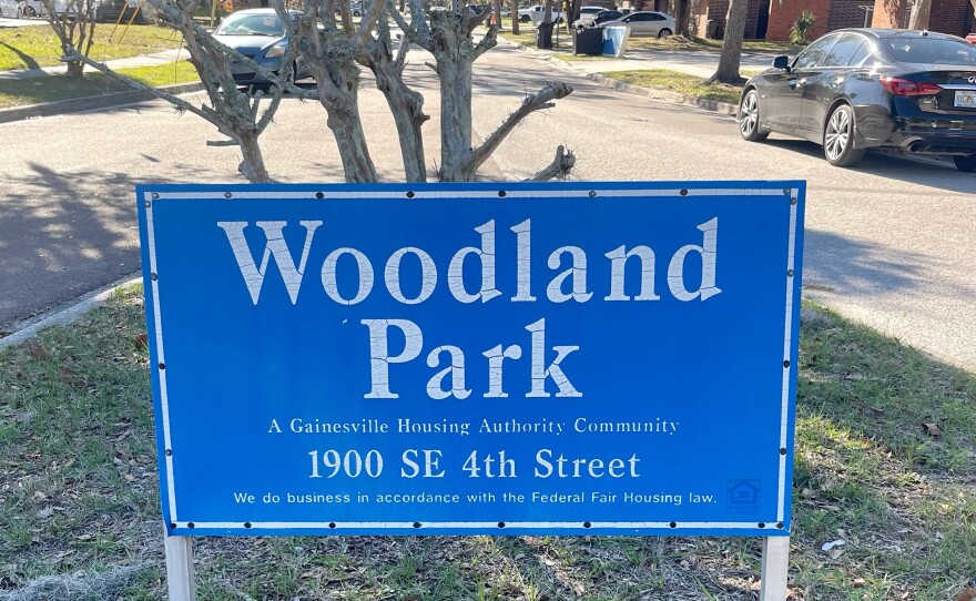 A wooden sign signals the entrance of the Woodland Park apartment complex.