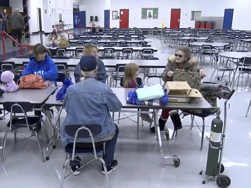 This image taken from video and provided by WTVQ shows people sitting at a table at Rockcastle Middle School which was being used as an evacuation center in Mt. Vernon, Ky., on Wednesday. People were evacuated from a nearby town after a CSX train derailed near Livingston, a remote town in Rockcastle County.
