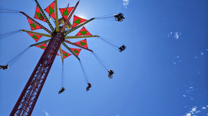 A photo looking up toward a carnival ride which features swings suspended from a tower. 
