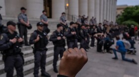 Protesters kneel and raise their arms if front of a row of police officers as they gather peacefully to protest the death of George Floyd at the State Capital building in downtown Columbus, Ohio, on June 1, 2020. (Seth Herald/AFP/Getty Images)