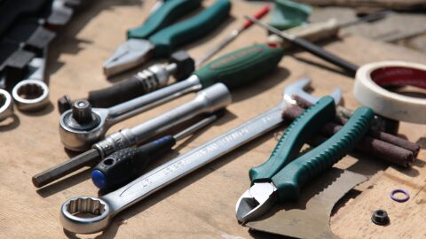 An assortment of hand tools on a wooden work table.