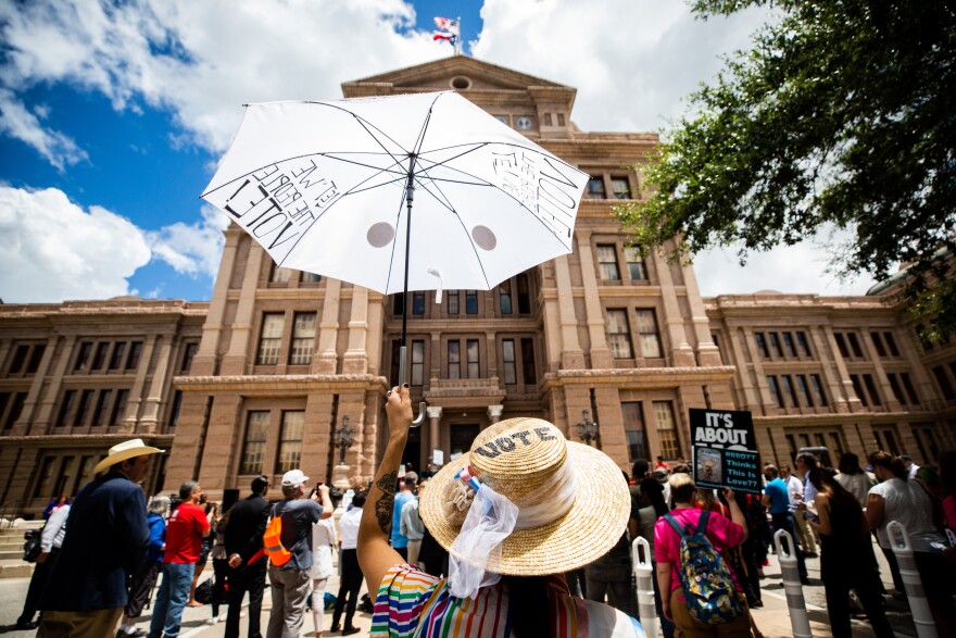 A woman holds an umbrella while participating at a protest outside the Capitol on July 8, 2021, as Texas Democratic lawmakers join multiple organizations to criticize proposed changes to election laws during the special legislative session that started this month. 