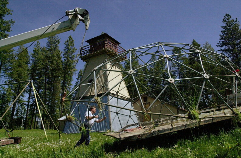 FILE - In this May 22, 2001, file photo, a worker moves children's play equipment away from a watch tower and off the property of the former headquarters of the neo-Nazi Aryan Nations, near Coeur d'Alene, Idaho. Nearly two decades after the compound was demolished, far-right extremists are maintaining a presence in the Pacific Northwest. White nationalism has been on the rise across the U.S., but it has particular resonance along the Idaho-Washington border. (AP Photo/Elaine Thompson, File)