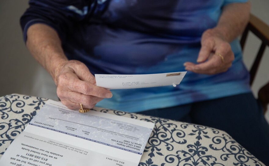 Judith Hall sits at her kitchen table to review the mail. She reviews a letter from an investor offering to buy her home for $196,000.