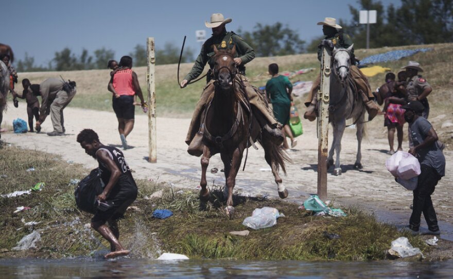 Border Patrol agents on horseback follow migrants trying to cross the Rio Grand River in Del Rio, Texas on Sunday.